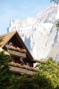Holzhaus mit Blumenkästen an den Balkonen vor hohen Bergen